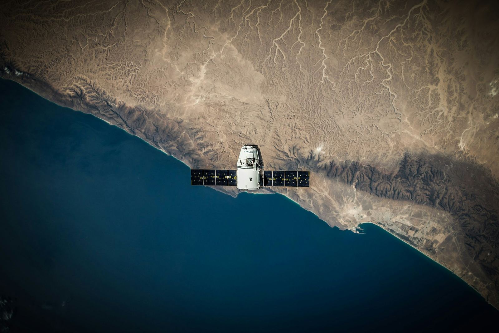 A satellite in orbit above a desert coastline
